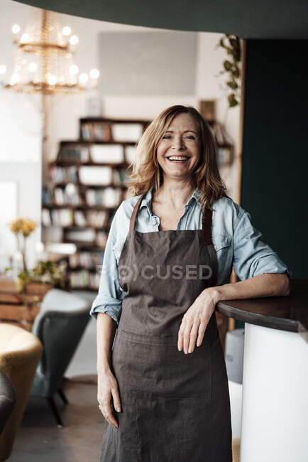 Glückliche Café-Inhaberin trägt Schürze, während sie im Café steht — Stockfoto