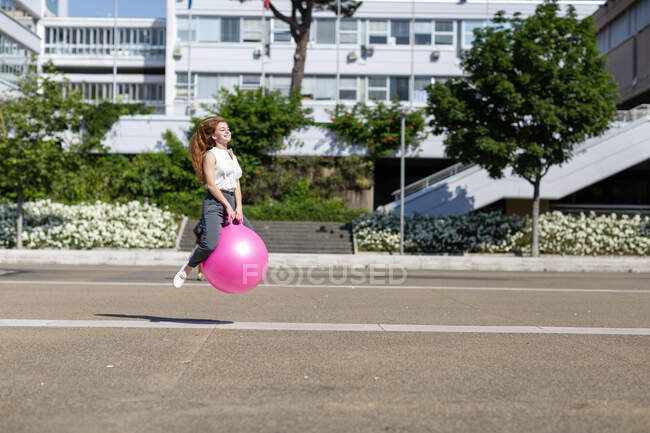 Unbekümmerte Geschäftsfrau hüpft an sonnigem Tag auf Ball — Stockfoto