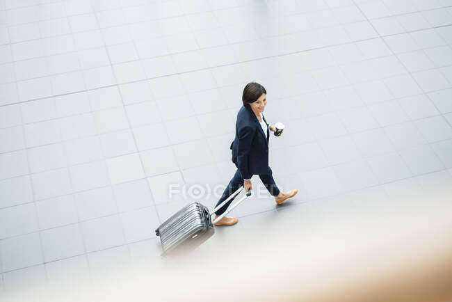 Businesswoman with suitcase walking in corridor — Stock Photo