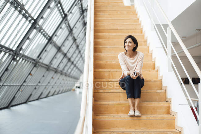 Geschäftsfrau überlegt, während sie auf Stufen im Flur sitzt — Stockfoto