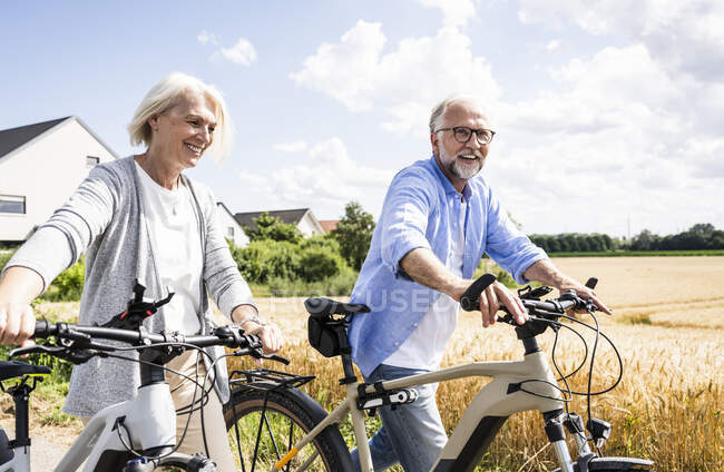 Улыбающаяся пара, гуляющая на велосипеде в солнечный день — стоковое фото