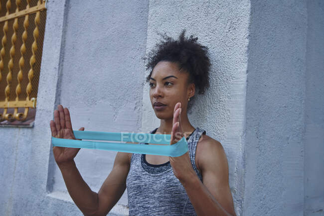 Metà donna adulta che si allena con fascia di resistenza davanti al muro — Foto stock
