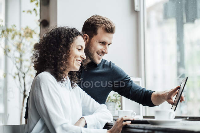 Pessoas de negócios sorrindo trabalhando no laptop enquanto sentado no café — Fotografia de Stock