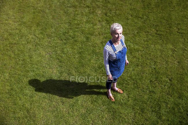 Mujer de pie sobre hierba en el jardín durante el día soleado - foto de stock
