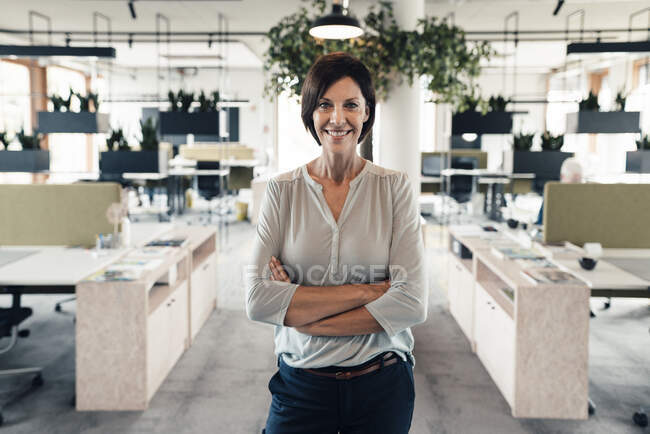 Confident businesswoman with arms crossed standing in office — Stock Photo