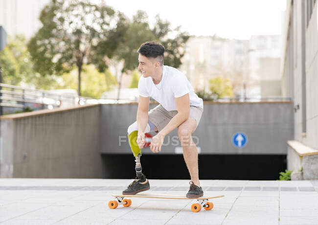 Souriant homme amputé skateboard contre le métro en ville — Photo de stock