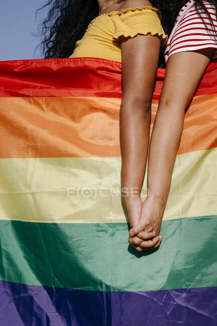 Lesbian women with rainbow flag holding hands — Stock Photo