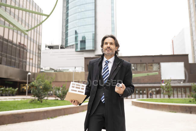Architecte masculin tenant un modèle architectural et un plan directeur dans un parc de bureaux — Photo de stock