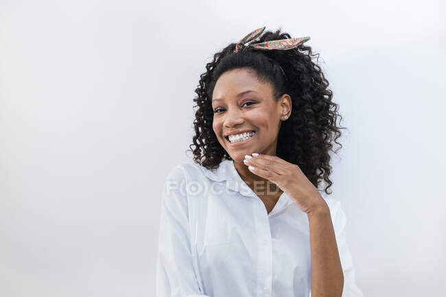 Glückliche Frau mit Hand am Kinn vor weißem Hintergrund — Stockfoto