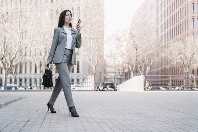 Donna d'affari matura che parla su smart phone mentre cammina in città — Foto stock