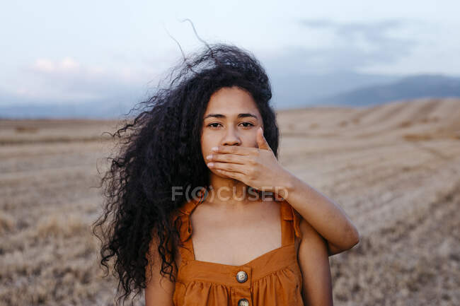 Jeune femme couvrant la bouche d'une amie avec la main dans la ferme — Photo de stock