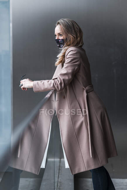Nachdenkliche Geschäftsfrau schaut weg, während sie sich während der Pandemie an Geländer lehnt — Stockfoto