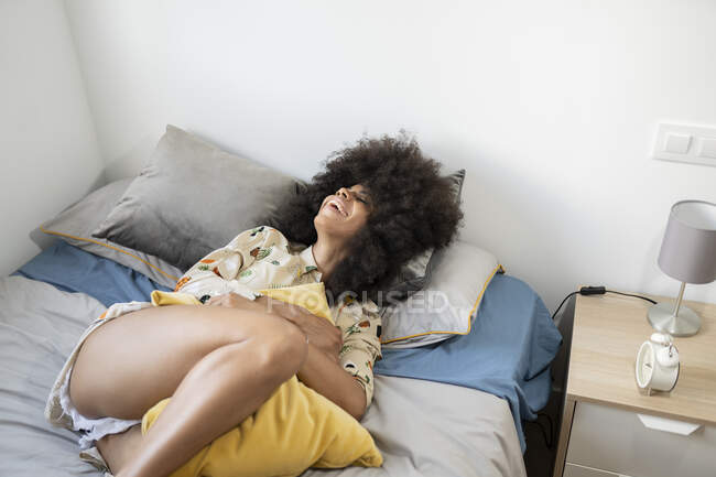 Smiling afro woman lying on bed at home — Stock Photo