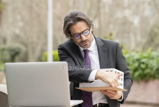 Male architect explaining architectural model during video call through laptop — Stock Photo