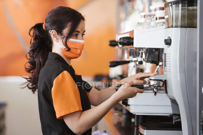 Waitress holding portafilter using espresso maker at cafeteria — Stock Photo
