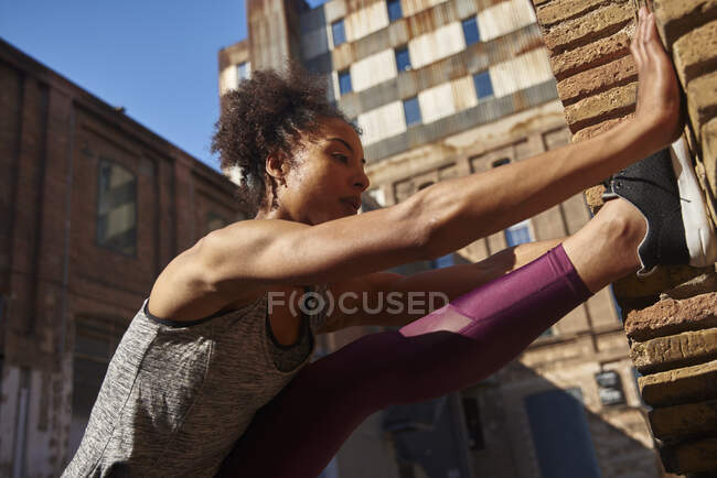 Deportista flexible estirándose mientras hace ejercicio en un día soleado - foto de stock