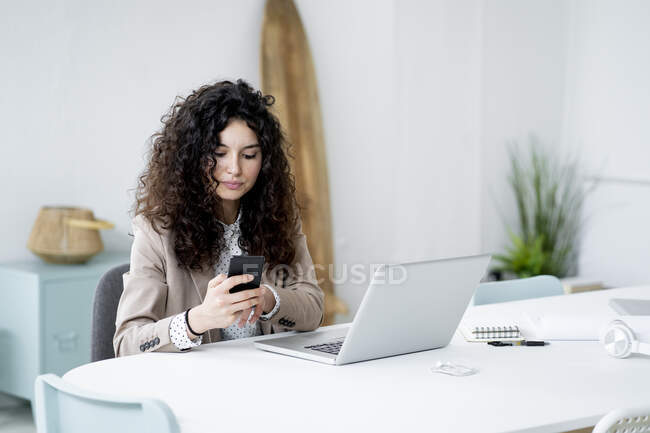 Imprenditrice che utilizza il telefono cellulare mentre lavora in ufficio — Foto stock