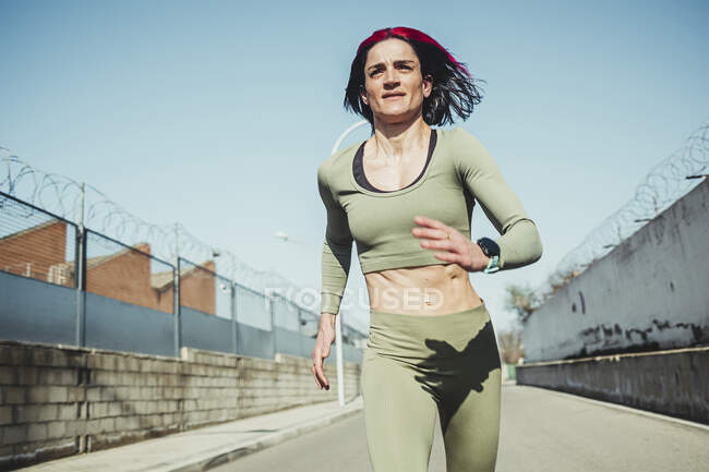 Mujer corriendo en el camino contra el cielo azul - foto de stock