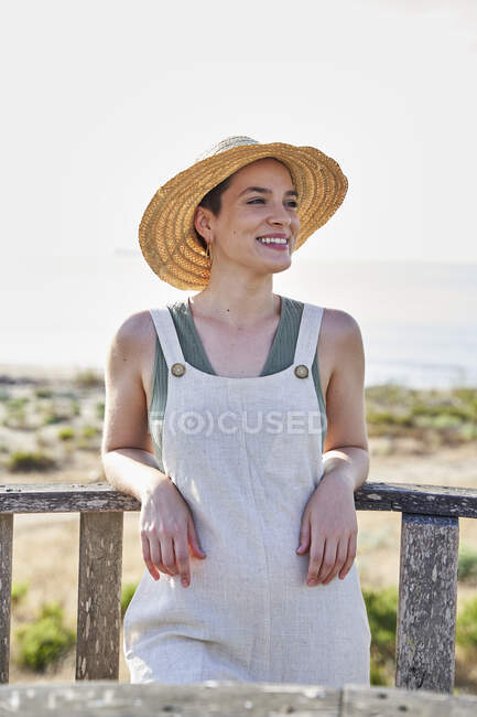 Sorrindo jovem mulher usando chapéu encostado no corrimão — Fotografia de Stock
