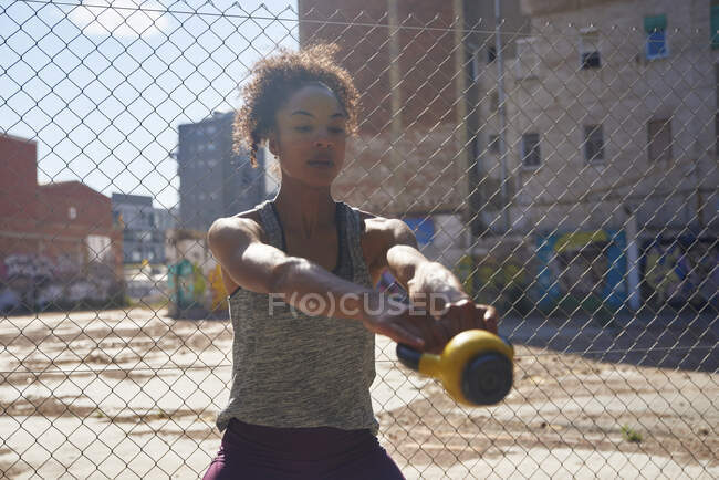 Atleta haciendo ejercicio con kettlebell delante de la cerca de eslabones de cadena - foto de stock