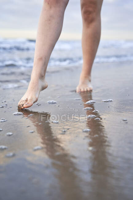 Jeune femme marchant au bord de l'eau — Photo de stock