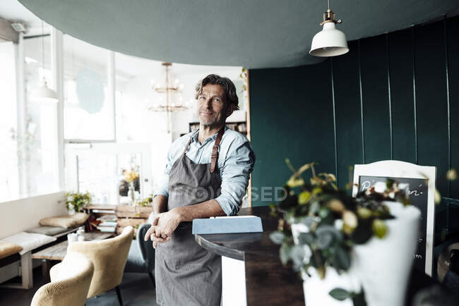 Maturo maschio caffè proprietario in piedi mentre appoggiato su tavolo — Foto stock