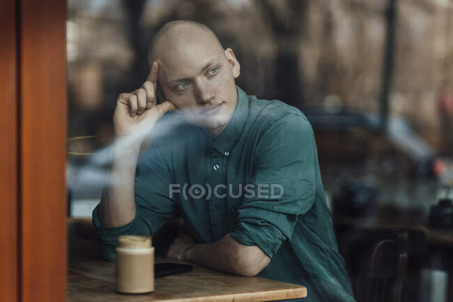 Pensativo dueño de café masculino mirando a través de la ventana - foto de stock