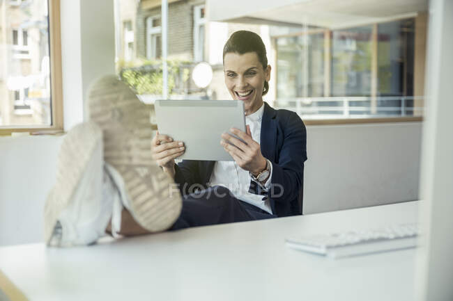 Femme d'affaires joyeux assister à un appel vidéo par tablette numérique dans le bureau — Photo de stock