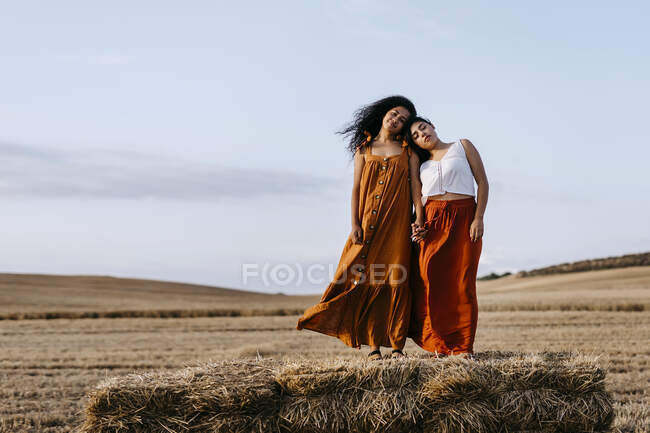 Donne con gli occhi chiusi che si tengono per mano mentre stanno in piedi sul fieno — Foto stock