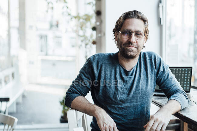 Selbstbewusster Mann sitzt am Laptop in Café — Stockfoto