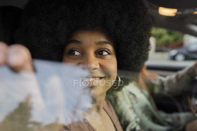 Souriant Afro femme regardant par la fenêtre de la voiture — Photo de stock