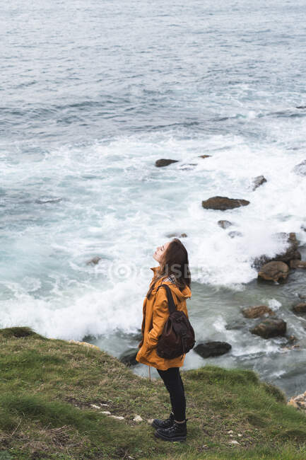 Молода жінка стоїть на скелі біля моря. — стокове фото