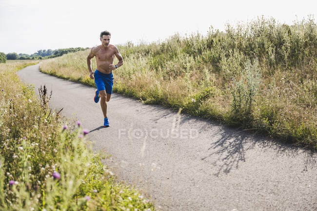 Hemdloser männlicher Athlet läuft auf Straße — Stockfoto