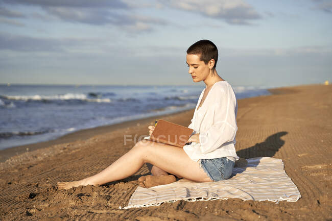 Woman writing in diary while sitting on blanket — Stock Photo