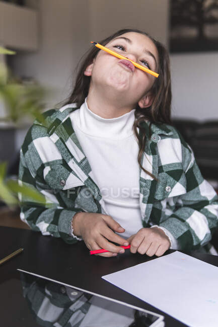 Дівчинка грає з олівцем за столом. — стокове фото
