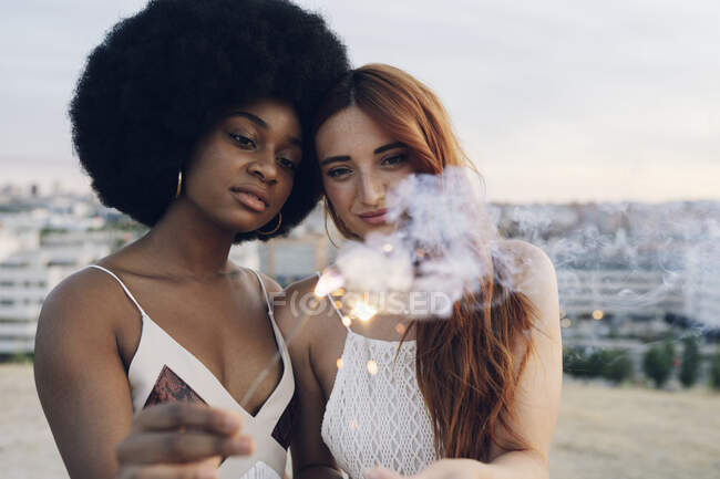 Lésbicas casal segurando sparklers durante o pôr do sol — Fotografia de Stock