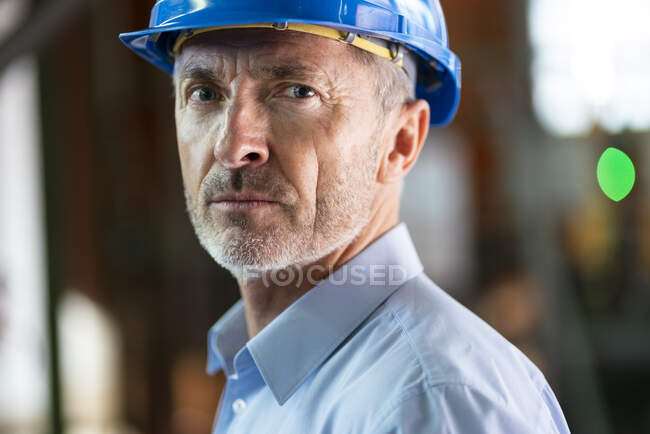 Mature male engineer with hardhat in industry — Stock Photo