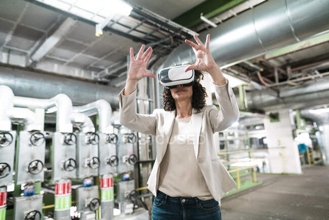 Femme d'affaires utilisant casque de réalité virtuelle tout en restant debout dans l'atelier — Photo de stock