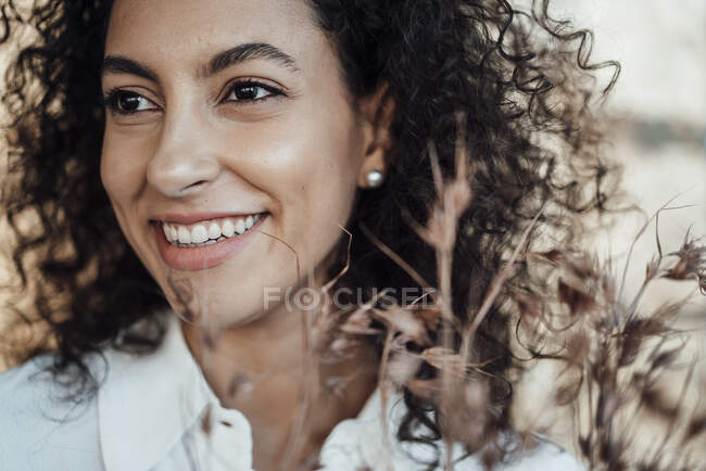 Mujer de negocios sonriente mirando hacia otro lado mientras está parado contra la pared - foto de stock