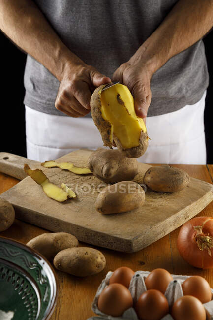 Partie médiane de l'homme épluchant les pommes de terre — Photo de stock