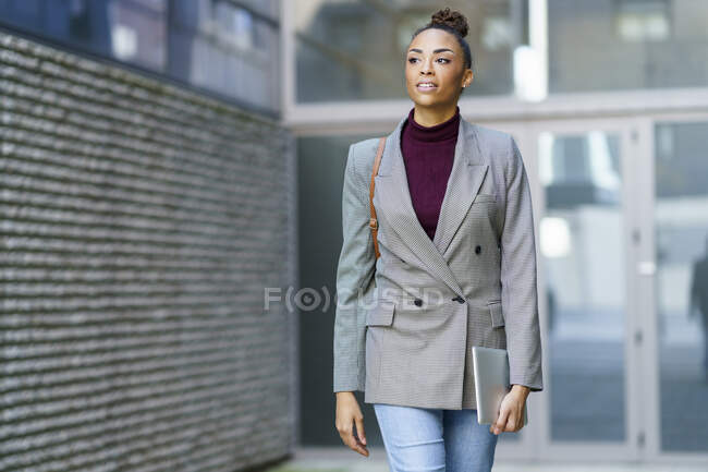 Молодая деловая женщина с цифровым планшетом во время прогулки против офисного здания — стоковое фото