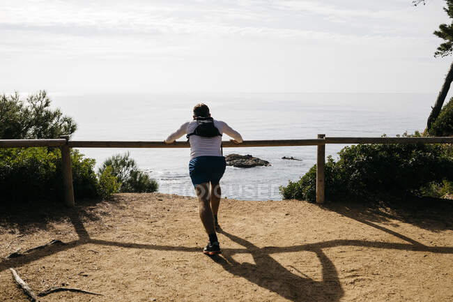 Man practicing push ups on wooden railing against clear sky — Stock Photo