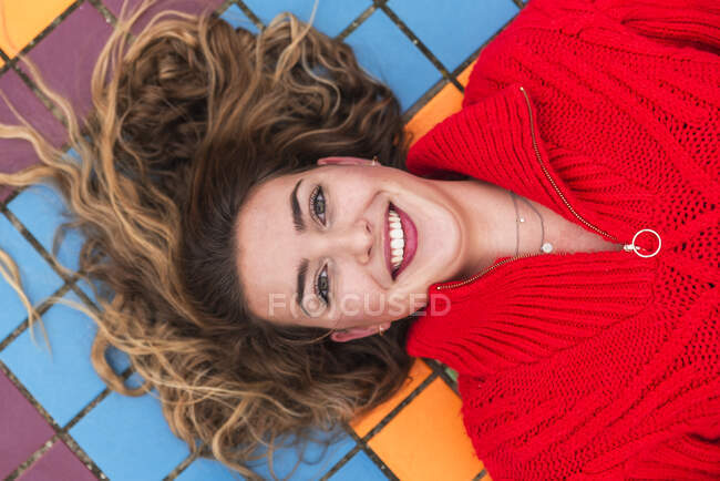 Happy woman lying on multi colored tiled floor — Stock Photo
