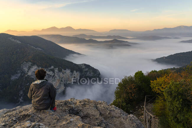 Männliche Touristen sitzen an einer Klippe und beobachten den Sonnenaufgang in der Furlo-Schlucht, Marken, Italien — Stockfoto