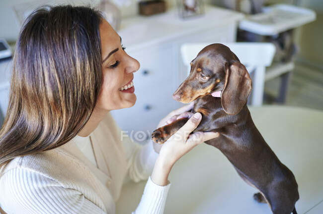 Smiling woman playing with dog at home — Stock Photo