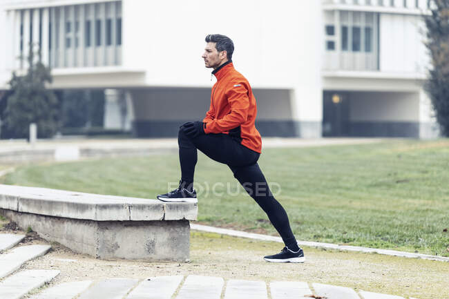 Deportista masculino determinado haciendo ejercicio de estiramiento en el parque - foto de stock