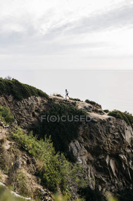 Man running on mountain against cloudy sky — Stock Photo
