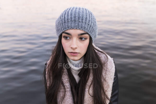 Задумчивая девочка-подросток против реки на закате — стоковое фото