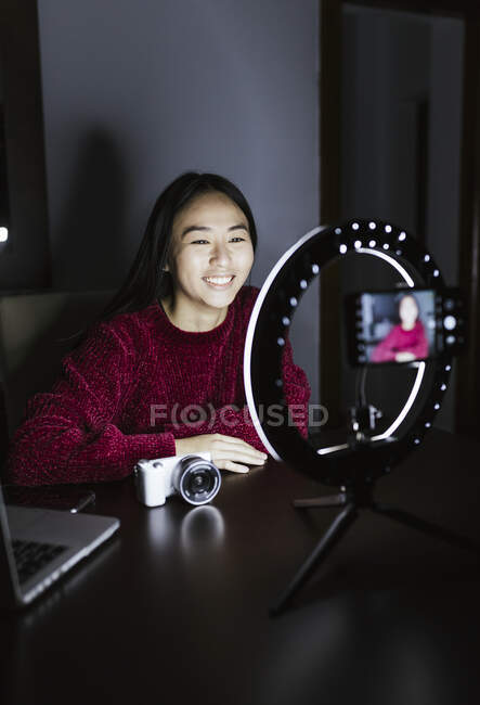 Sorridente donna vlogging circa la nuova fotocamera in camera oscura — Foto stock