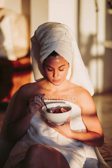 Woman wearing towel holding fruit bowl at home — Stock Photo